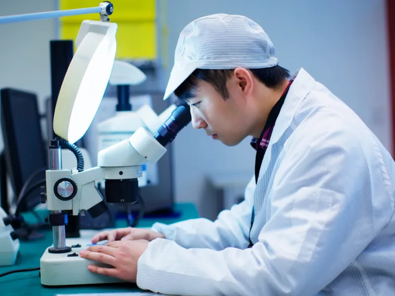 Researcher looking through a microscope.