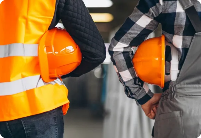 Two people holding orange hardhats.