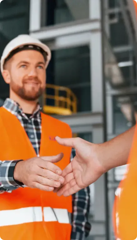 Two men in orange PPE shaking hands.