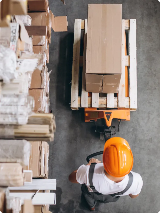 Man in a warehouse pulling a pallet.