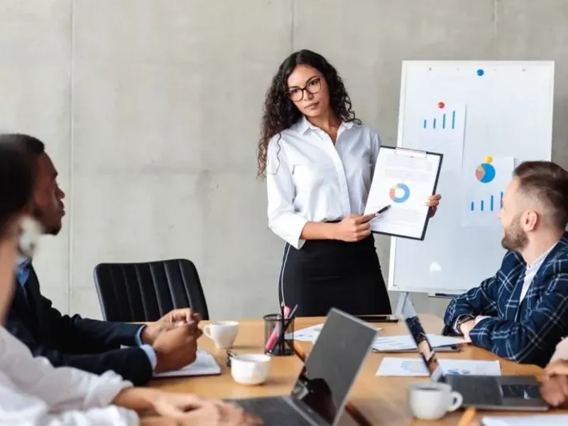 A young professional giving a presentation to the team using charts.