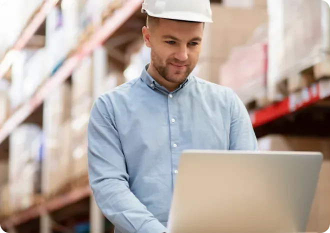 Man wearing a hard hat using a computer.