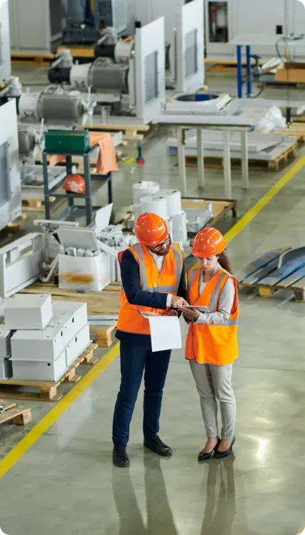 Man and woman in a warehouse wearing orange PPE.
