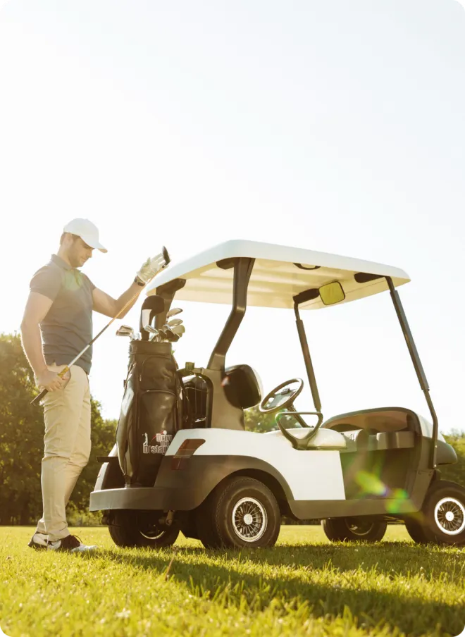 Man golfing with a golf cart.