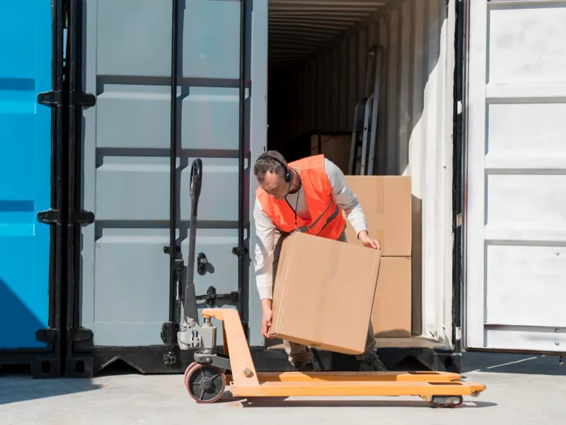 A man loads a box from a truck onto a dolly