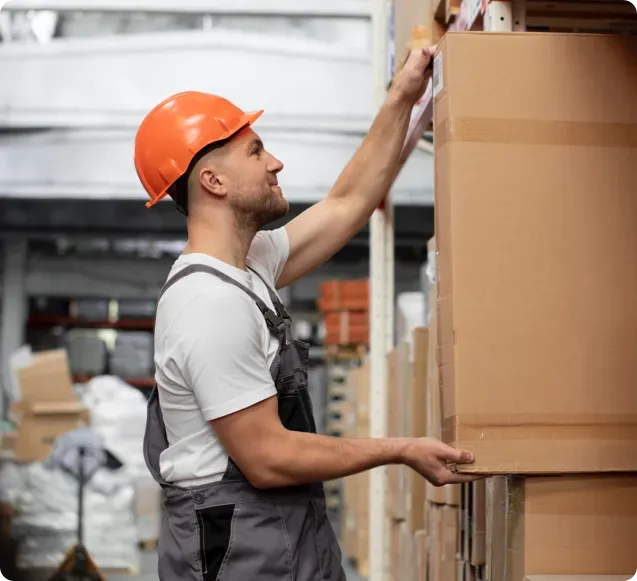 Man in a warehouse holding a box.
