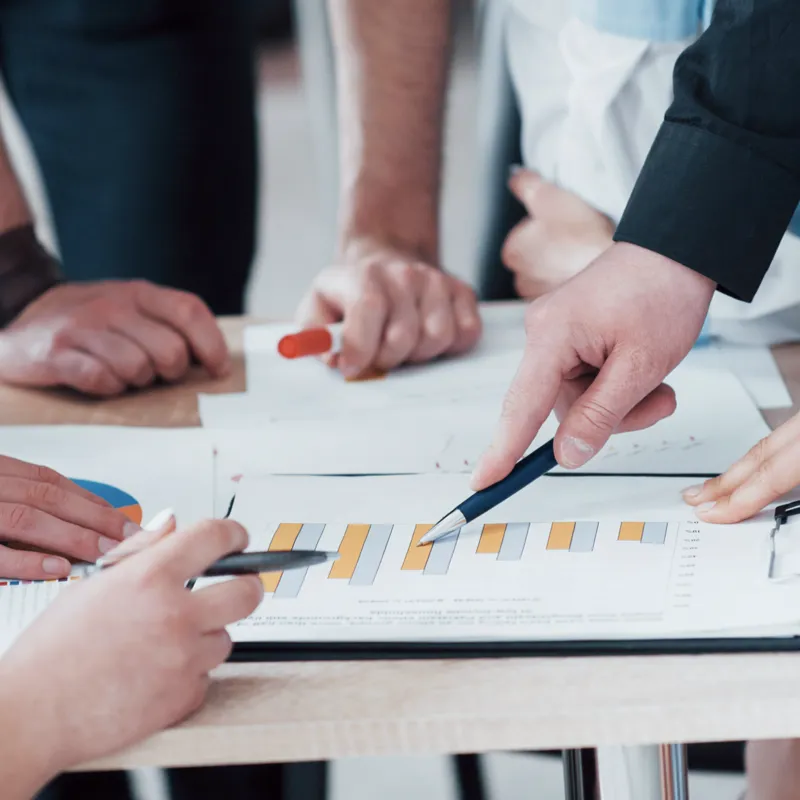 A group of coworkers discussing and point to a bar chart.