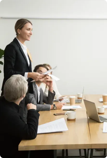 Woman presenting at a conference table.