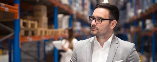 Portrait Successful Businessman Manager CEO Holding Tablet Walking Through Warehouse Storage Area Looking Towards Shelves