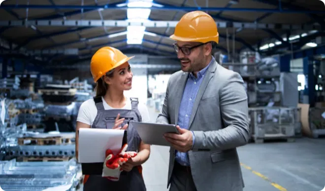Coworkers wearing construction hats in a warehouse.