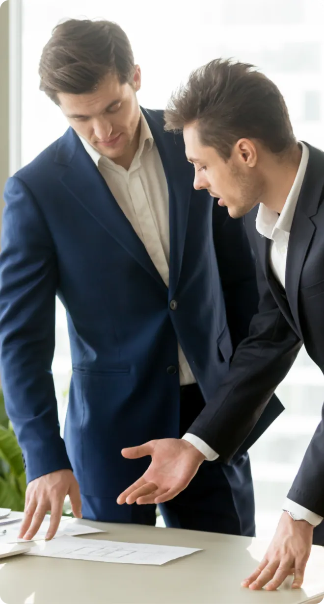 Two men in suits reviewing a contract.