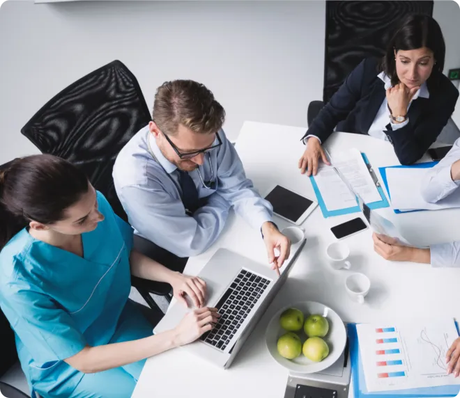 Co-workers meeting around a laptop at a conference table.