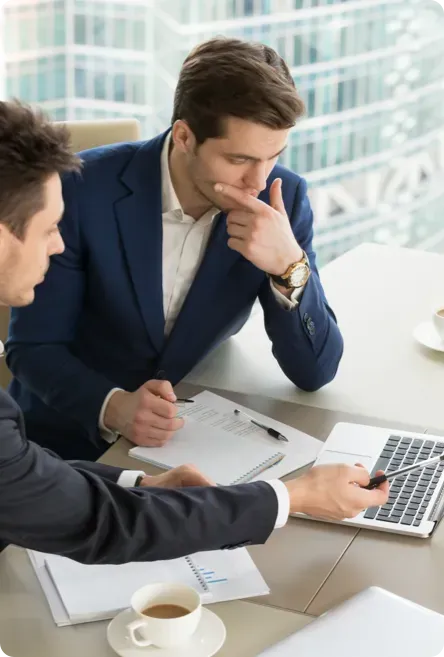 Two men working over a laptop.