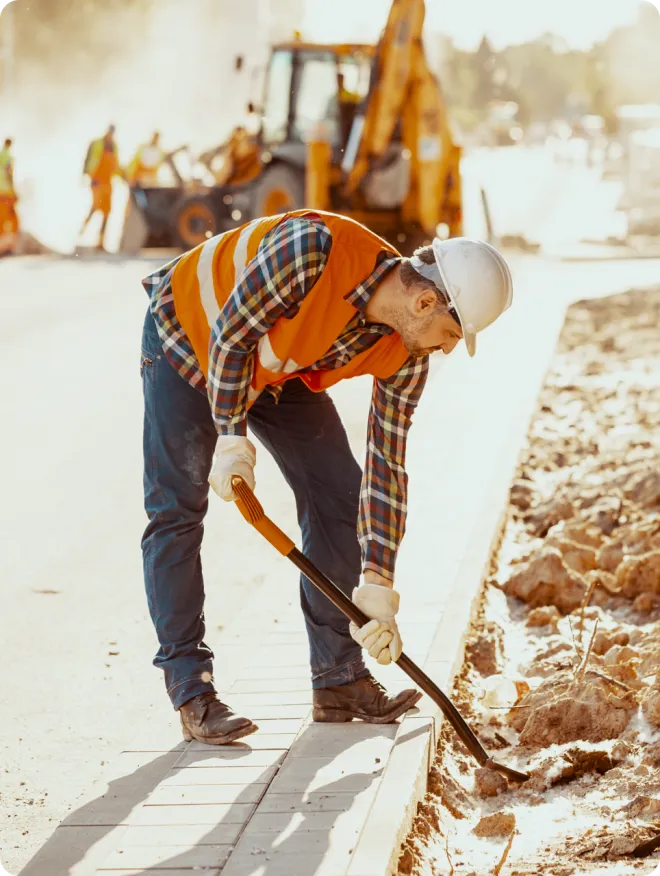 Man in orange PPE using a shovel.