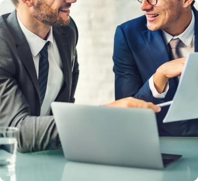 Two men laughing over a laptop.